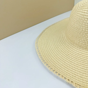 Detail shot of beige straw sun hat featuring intricate lace-edge weave and fine textures