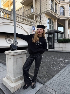Outdoor street style shot of oversized black pullover sweatshirt and leather trousers