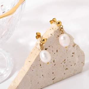 Detail of gold pearl earrings hanging on stone props with soft lighting and luster