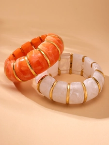 Detail of marble pattern resin bracelets with golden metal spacers in warm sun shadow