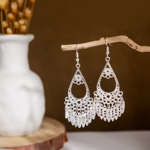 Detailed close-up of bohemian silver earrings with hollow teardrop design and leaf tassels