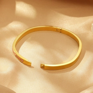 Bracelet ovale en acier titane doré orné de zircons roses sur soie champagne