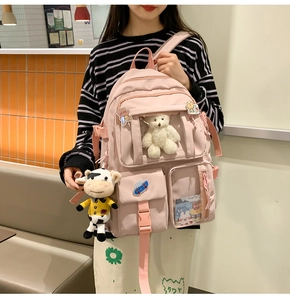 Zaino rosa da studentessa con orsetto di peluche e spille in un ambiente accogliente