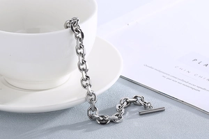 Detail of silver stainless steel OT toggle clasp chain hanging from a white ceramic cup