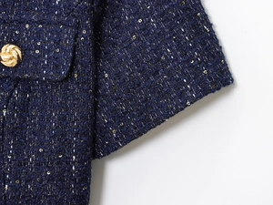Dettaglio del tessuto in tweed blu navy con bottoni dorati e paillettes blu