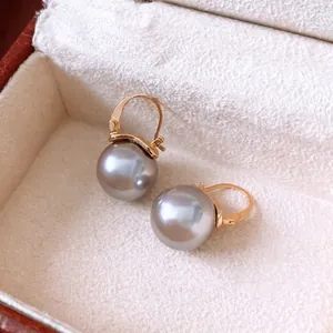 Boucles d'oreilles dorées avec grandes perles de verre gris argenté dans un écrin