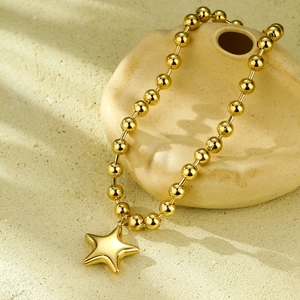 Detailed close-up of a gold ball chain necklace featuring a polished star pendant