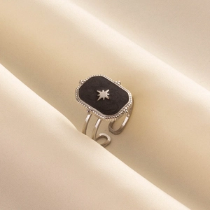 Detail of minimalist stainless steel octagram ring on soft silk background texture