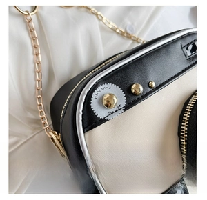 Detail of camera-shaped crossbody bag with gold zipper and smooth PU leather texture