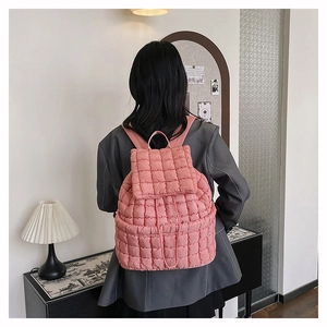 Zaino trapuntato rosa mostrato dal retro su una modella con un blazer grigio
