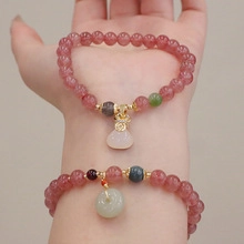 Detail of pink strawberry crystal beaded bracelets with golden lucky bag and jade pendants