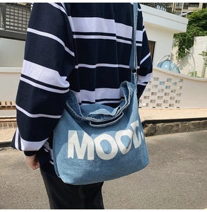Detailed close-up of a blue denim crossbody bag featuring a white printed MOOD logo