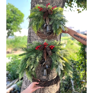 Bohemian Christmas wreaths with pine needles, red berries and bells on rattan rings