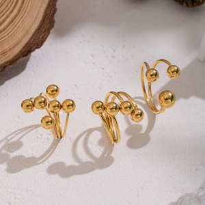 Minimalist gold ball open rings made of waterproof stainless steel on white stone base