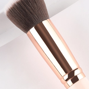 Pink flat top foundation brush with dense synthetic bristles and rose gold ferrule