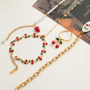 Detail view of 18K gold stainless steel jewelry set with cherry and strawberry enamel