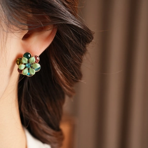 Close-up of vintage flower earrings with blue green enamel and crystals on a model