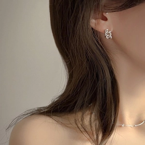 Detailed view of silver woven twist earrings worn by a model for a stylish look