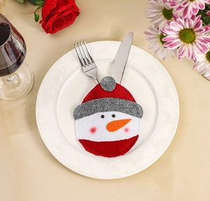 Close-up of a festive snowman cutlery holder with silver fork and knife on a plate