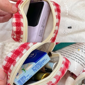 Detailed interior of red plaid tweed storage bag showing capacity for lipstick and power bank