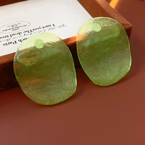 Detail of light green resin earrings with a brushed texture and organic shape