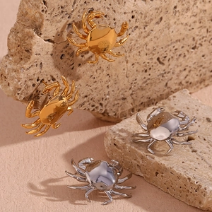 Primer plano de pendientes de cangrejo en oro de 18K y plata sobre piedra natural