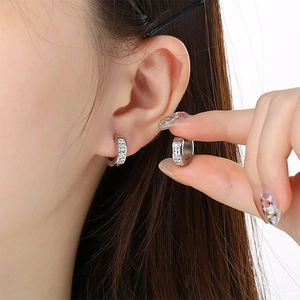 Detail of silver huggie hoop earrings with micro-paved clear crystals on model