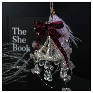 Detail view of crystal chandelier ornament with red velvet bow and purple feathers