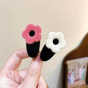 Dettaglio delle mollette per capelli a fiori in velluto rosa e bianco con centri neri