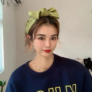 Elegant green satin bow headband worn by a model to show front view fit and style
