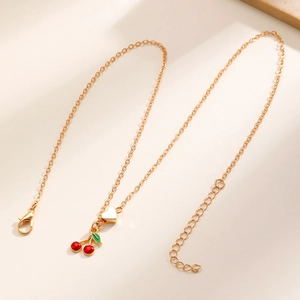 Dettaglio della collana dorata con ciondoli a forma di ciliegia e cuore e chiusura a moschettone