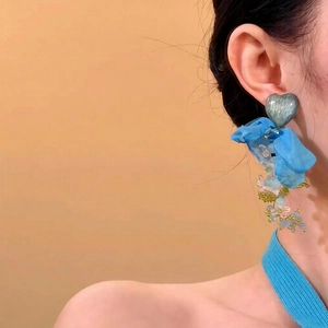 Détail de clip d'oreille cœur avec fleur en organza bleu et pompons perlés colorés