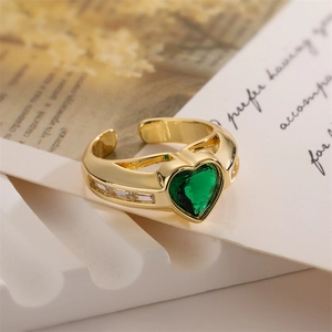 Detail of green heart zirconia ring on vintage background with gold open band