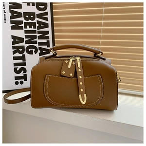 Détail du sac en cuir marron avec surpiqûres blanches et rivets en métal doré