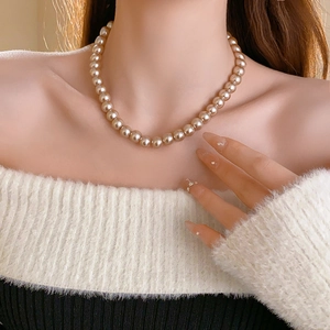 Close-up of elegant single-strand pearl choker necklace in champagne gold on a model