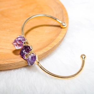 Macro shot of natural raw amethyst clusters set on a polished gold-plated open bangle