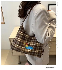 Detail of brown checkered shoulder bag with cute cartoon dog embroidery and stylish strap