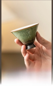 Macro detail of handmade ceramic tea cup showing emerald green kiln transformation glaze
