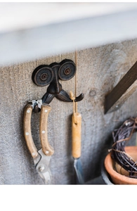 Detail van een vintage gietijzeren wandhaak met snor gemonteerd op rustiek hout