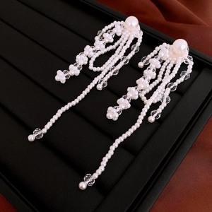 Detail shot of long tassel earrings with white pearls and faceted crystal beads on silk