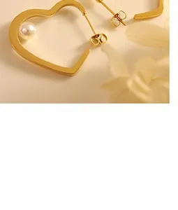 Detailed view of gold heart earrings with white faux pearl in a minimalist matte finish