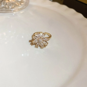 Detail of a golden flower-shaped adjustable ring with clear sparkling rhinestones