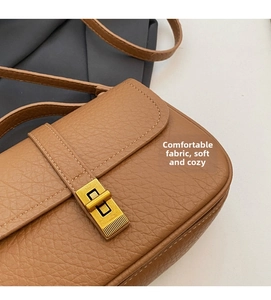 Close-up of brown pebbled leather texture and golden rectangular metal twist lock on bag