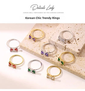 Detail of bow-shaped rings with colorful zircon stones on a textured stone display