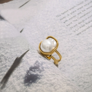 Macro shot of a golden ring featuring a large white baroque pearl and double-layer band