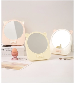 Dettaglio di specchi da trucco rotondi con orecchie di gatto e fiocchi in rosa, beige e bianco