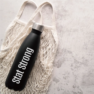Detail view of a black matte stainless steel sports bottle in a white woven rope net bag
