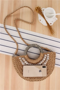 Detailed top view of a semi-circular straw bag with natural shells and woven handles