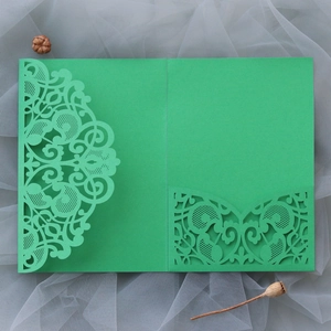 Detail of laser-cut green wedding invitation cover with elegant lace patterns on tulle
