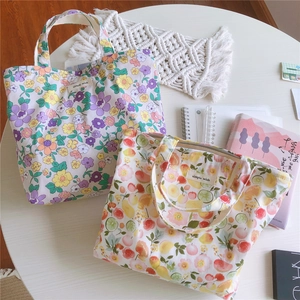 Détail de sacs cabas en toile à motifs floraux et fruités avec étiquette tissée blanche